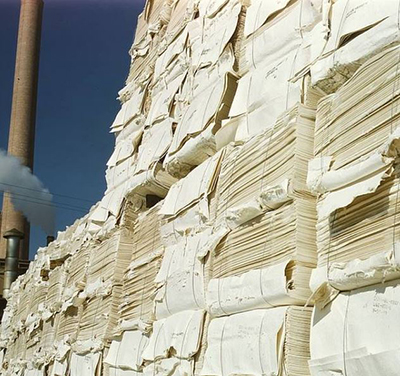 A large pile of stacked paper in front of a wall