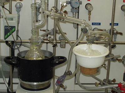 A pot of liquid being poured into a white bowl in a laboratory setting